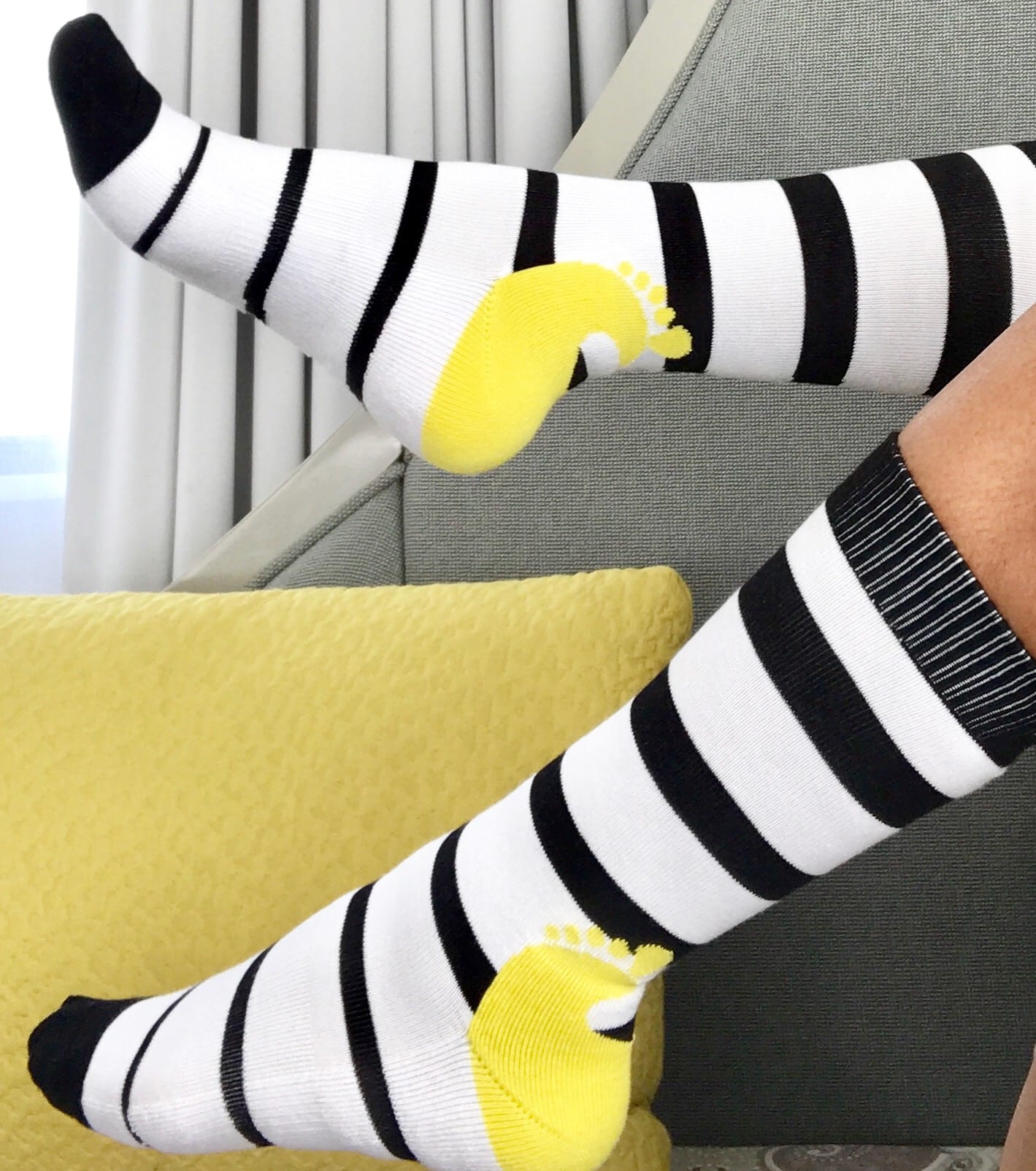 Women's leg wearing a pair of black and white striped magnetic SoleMate Sox that never go missing.
