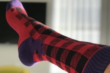 Woman's leg wearing a pair Buffalo Plaid SoleMate Sox magnetic socks holiday socks