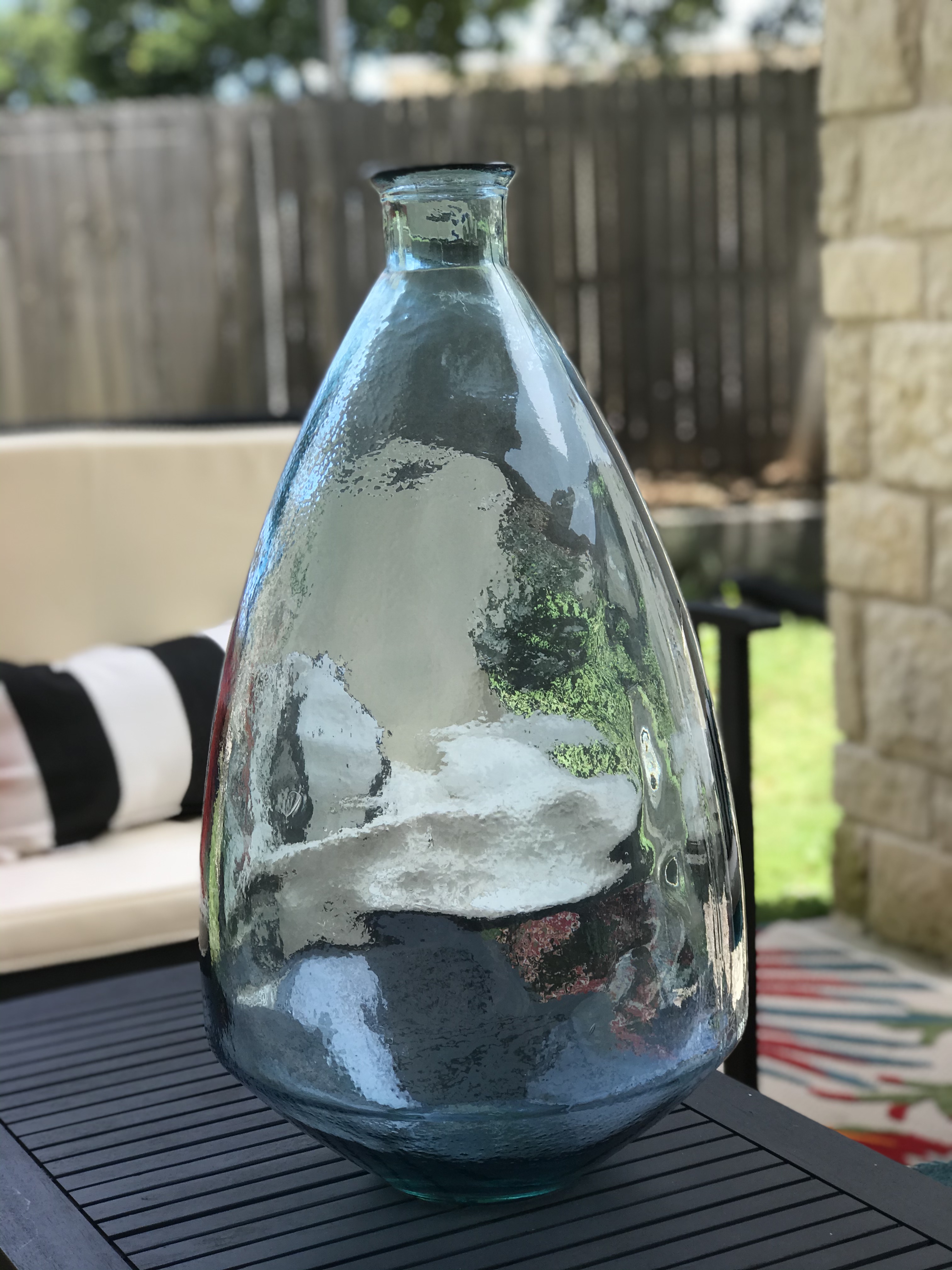 ReStylist Catenya McHenry creates an outdoor space by adding a tall hand blown turquoise vase from Home Goods