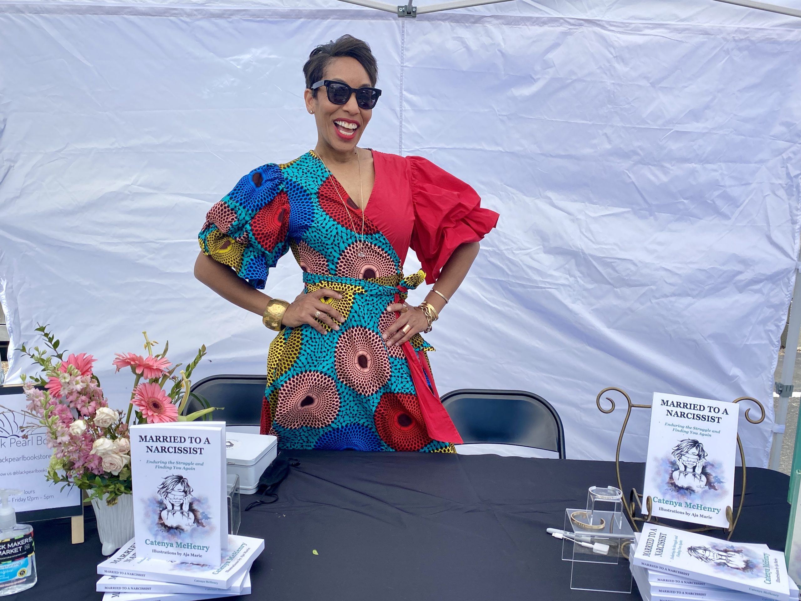 Wearing a red African print Tribe brand dress, Catenya McHenry, author of Married to a Narcissist: enduring the Struggle and Finding You Again signs copies of her book at Black Pearl Bookstore in Austin, Texas on Independent Bookstore Day