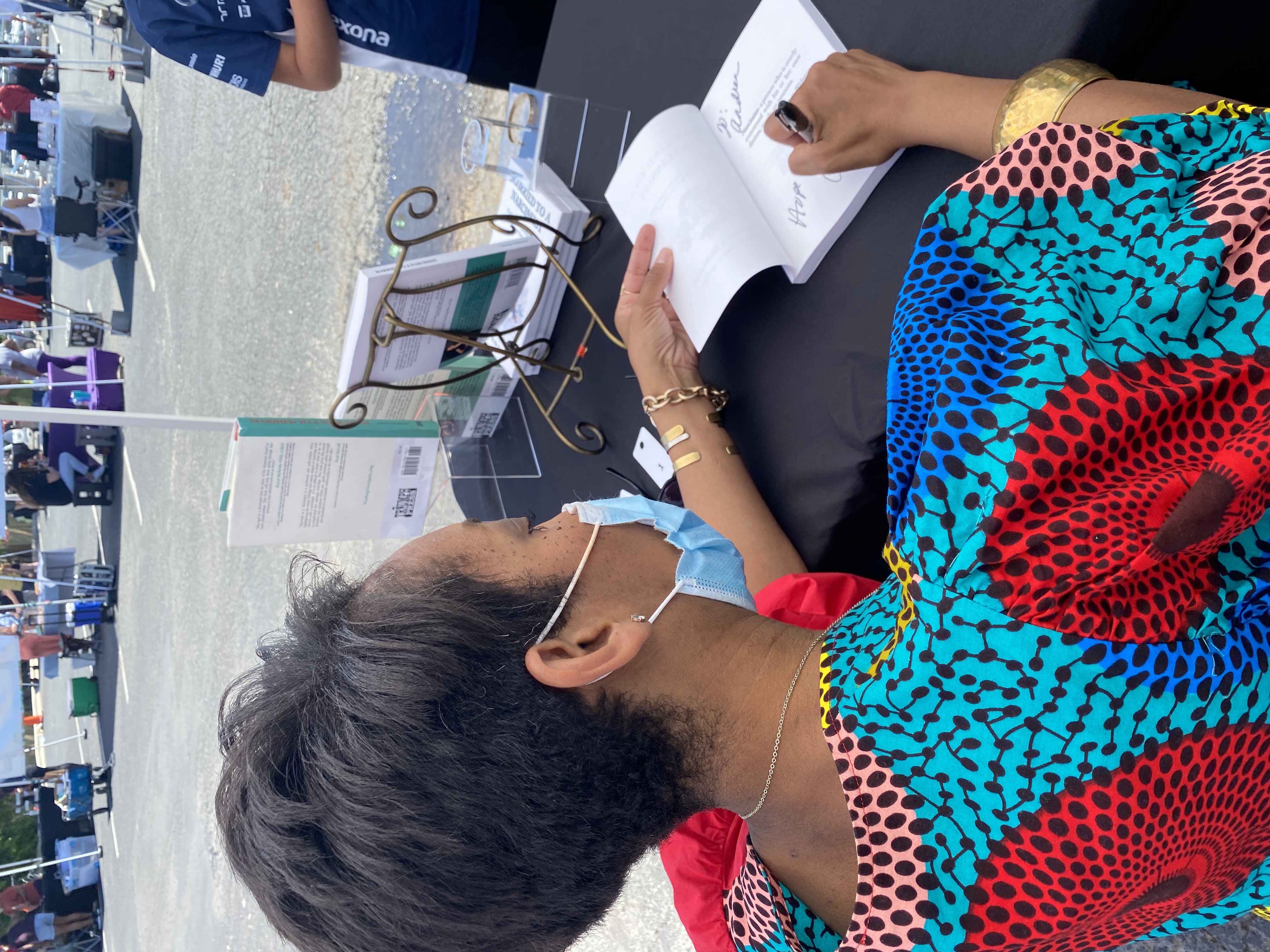 Wearing a red African print Tribe brand dress, Catenya McHenry, author of Married to a Narcissist: enduring the Struggle and Finding You Again signs copies of her book at Black Pearl Bookstore in Austin, Texas on Independent Bookstore Day