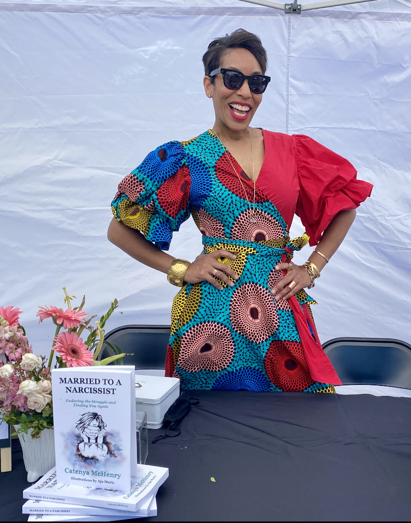 Wearing a red African print Tribe brand dress, Catenya McHenry, author of Married to a Narcissist: enduring the Struggle and Finding You Again signs copies of her book at Black Pearl Bookstore in Austin, Texas on Independent Bookstore Day